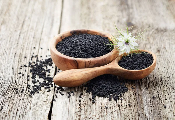 Aceite Comino Negro Con Flor Sobre Tabla Madera — Foto de Stock