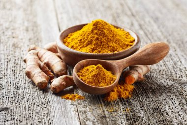 Ahşap arka planda zerdeçal kökü ve tozu