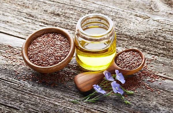 Aceite de lino y semillas sobre fondo de madera — Foto de Stock