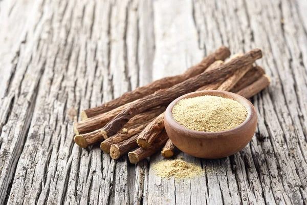 Licorice dry root with powder on wooden background — Stock Photo, Image