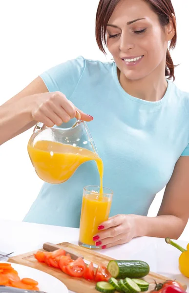 Smiling beautiful female pouring juice from jug into glass isola — Stock Photo, Image
