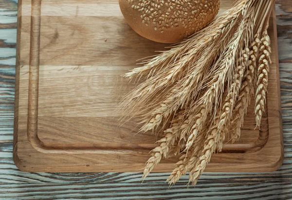 Carving board bread bunch of rye ears on wooden surface — Stock Photo, Image