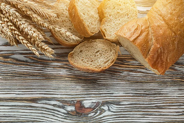 Crusty sliced bread rye ears on wooden surface — Stock Photo, Image