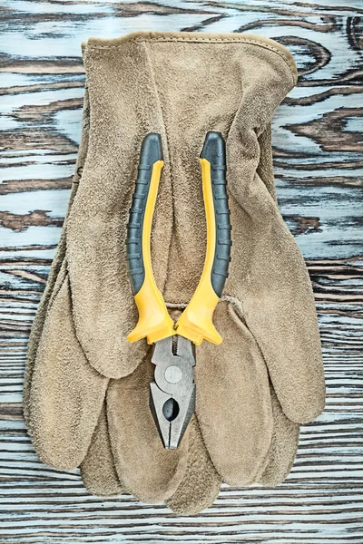 Leather safety gloves pliers on wooden board — Stock Photo, Image