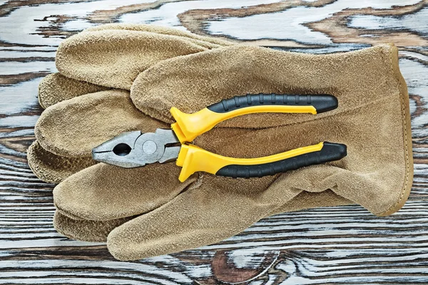 Leather safety gloves gripping tongs on wooden board — Stock Photo, Image