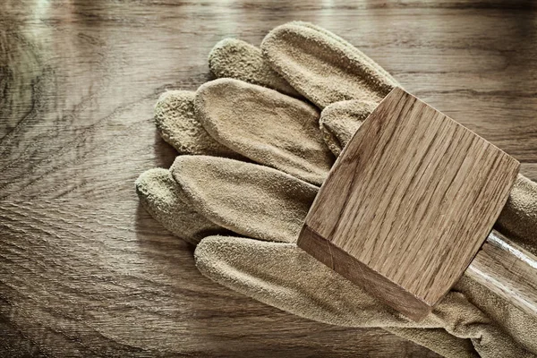 Par de guantes protectores de cuero mazo de madera sobre tabla de madera — Foto de Stock