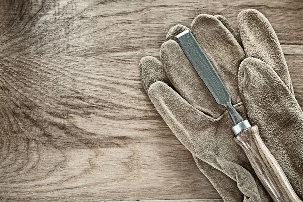 Firmer chisel safety gloves on wooden board.