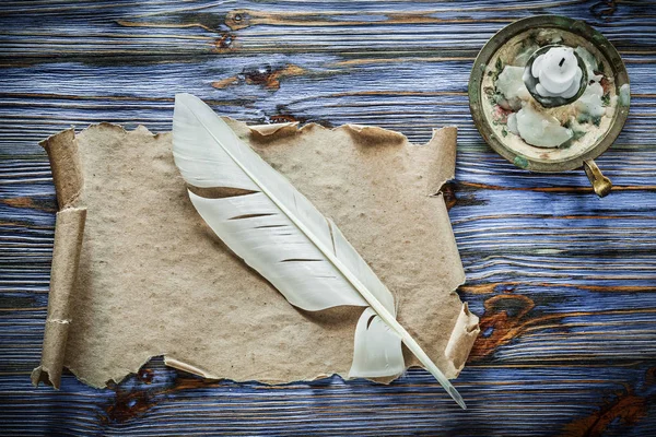 Vintage kağıt kaydırma tüy şamdan mavi ahşap zemin üzerine.