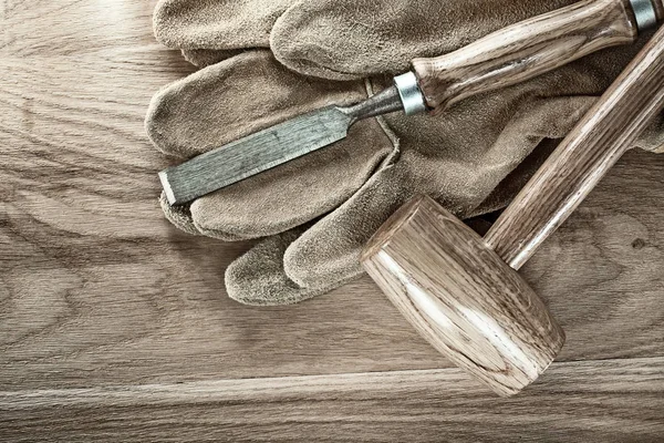 Ahşap tahta üzerinde topak çekiç düz keski koruyucu eldivenler.