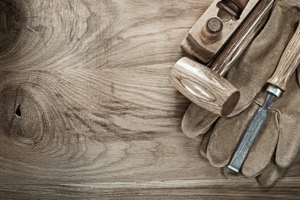 Wooden mallet shaving plane chisel protective gloves on wood board.