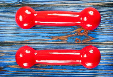 Antika ahşap tahta üzerinde kırmızı dumbbells çifti.