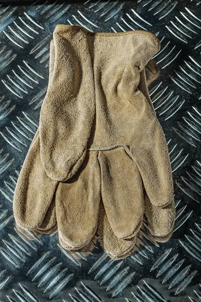 Leather protective gloves on corrugated metal sheet