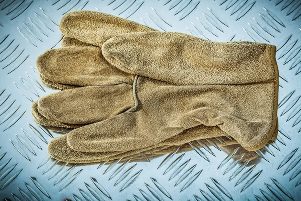 Lederen veiligheidshandschoenen op gecanneleerde metalen textuur — Stockfoto