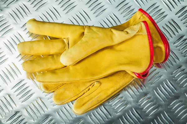 Leather protective gloves on corrugated metal texture.