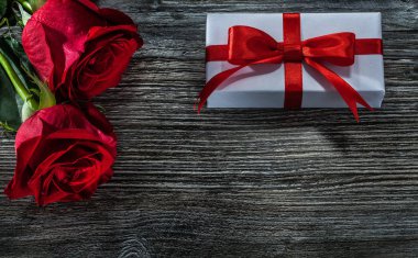 Ahşap tahta üzerinde kırmızı gül beyaz hediye kutuları.