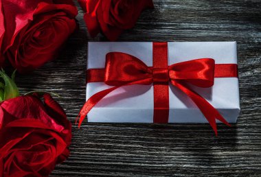 Beyaz hediye kutusu doğal kırmızı gül ahşap tahta üzerinde.