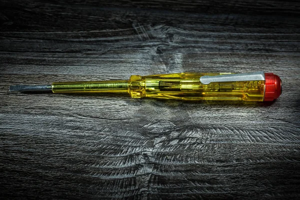 Insulated screwdriver on wooden board.