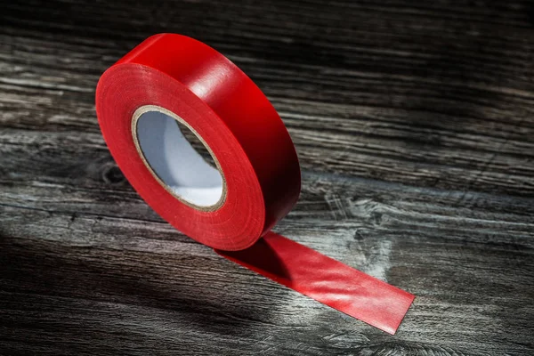 Red rolled duct tape on vintage wooden board.