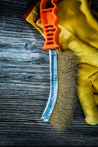 Hand wire brush protective gloves on vintage wooden board.