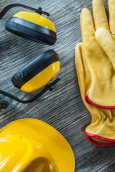 Protective gloves hard hat earmuffs on wooden board.