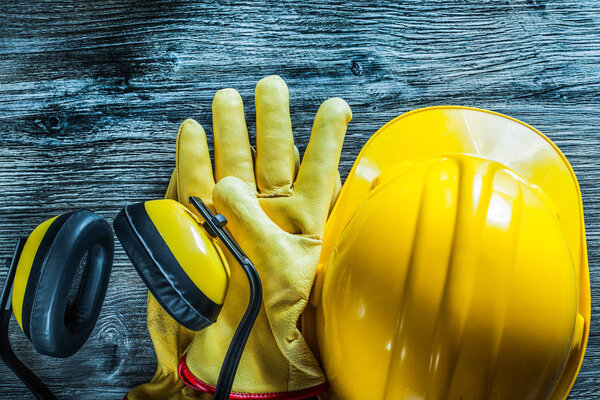 Earmuffs safety gloves hard hat on wooden board.
