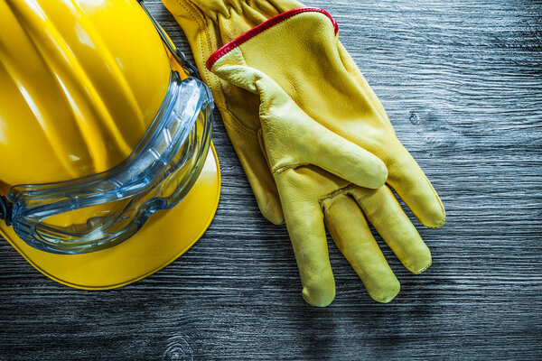 Safety gloves hard hat goggles on vintage wooden board.