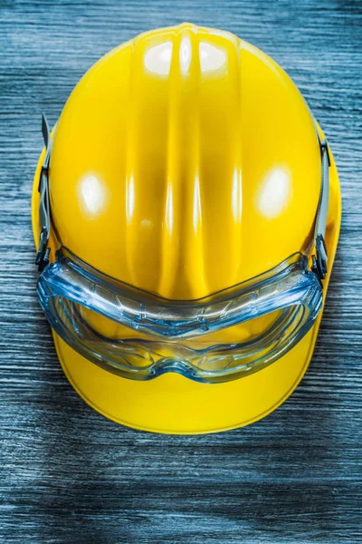 Safety building helmet goggles on vintage wooden board.