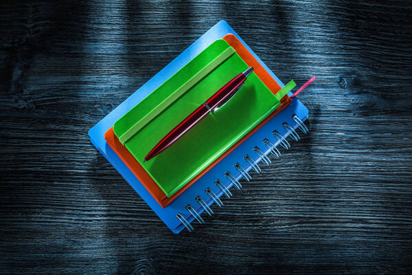Pile of notebooks pen on vintage wooden board.