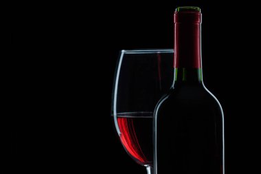 şişe ve siyah arka plan üzerinde kırmızı şarap kadehinin görünümü kapatın