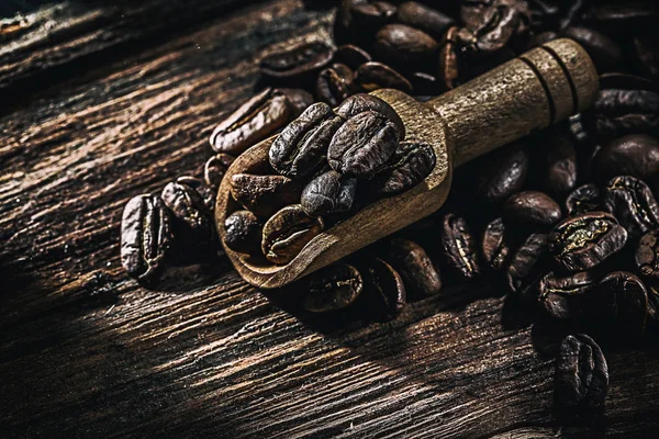 木板上的勺子里的全麦咖啡种子 — 图库照片