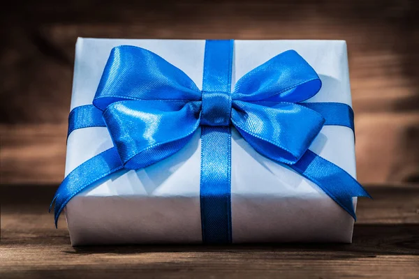 Confezione regalo bianca con nastro blu su legno vintage — Foto Stock