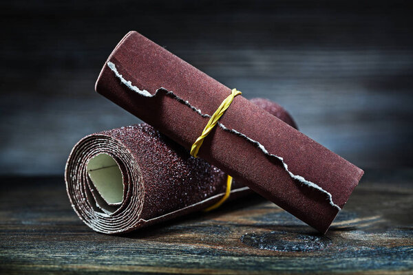 abrasive sandpaper rolled up on vintage wood