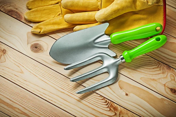 Gartengabel und Handspaten mit gelben Handschuhen auf Holzbrettern — Stockfoto