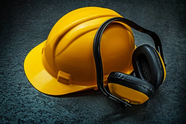 Capacete amarelo e fones de ouvido no fundo preto — Fotografia de Stock