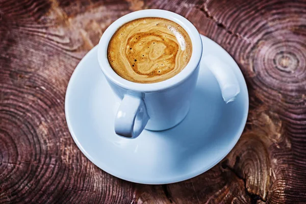 Загальний вигляд капучіно в білій чашці кави на вінтажному дерев'яному хресті — стокове фото