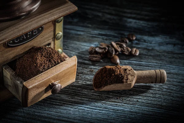 Molino de café cucharada granos en tablero de madera —  Fotos de Stock