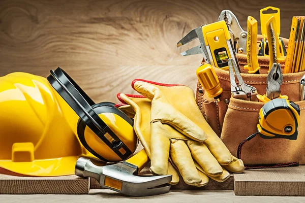 Cascos auriculares guantes de martillo y correa de herramientas con la construcción de —  Fotos de Stock