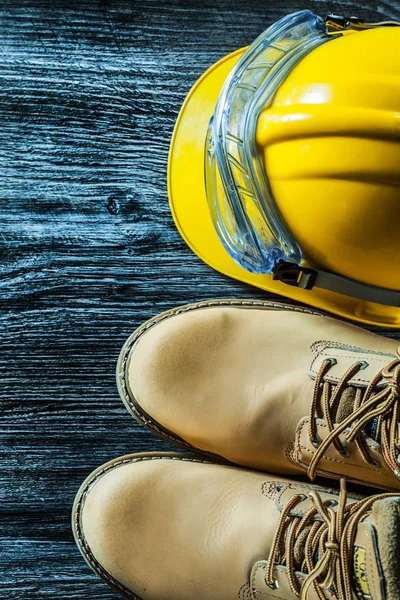 Botas de segurança óculos de construção capacete na placa de madeira vintage — Fotografia de Stock