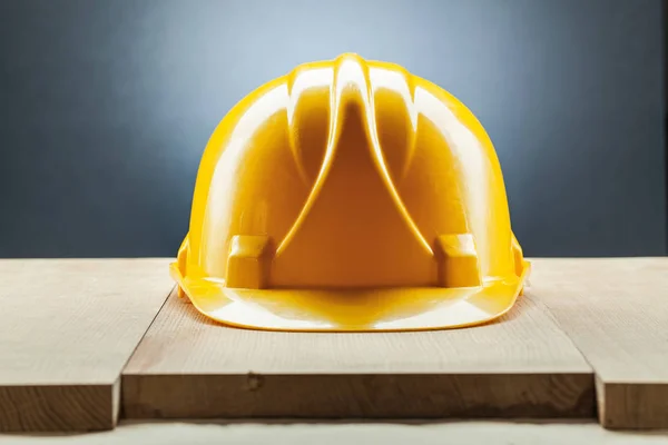 Yellow construction helmet on wood board — Stock Photo, Image