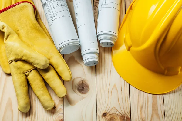 Gele handschoenen blauwdrukken en bouw helm op hout — Stockfoto