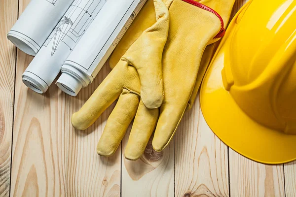 Blueprints yellow gloves and construction helmet on wood boards — Stock Photo, Image