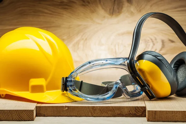 Safety tools. blue goggles yellow helmet and earphones on wood b — Stock Photo, Image