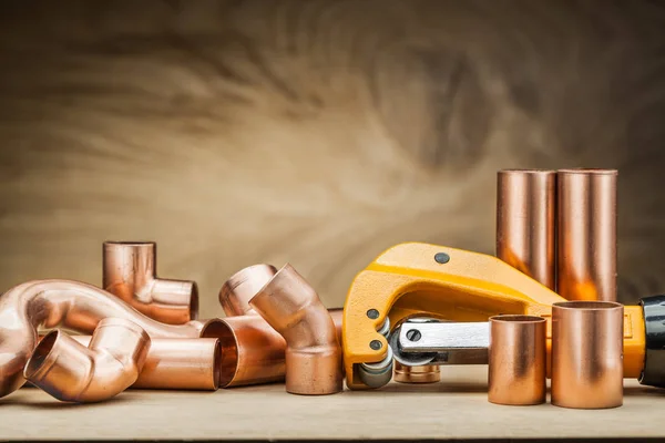 Set of copper pipe fittings and  pipe cutter on vintage wood bac — Stock Photo, Image