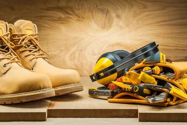 Buty i słuchawki na taśmie narzędziowej z narzędziami budowlanymi — Zdjęcie stockowe