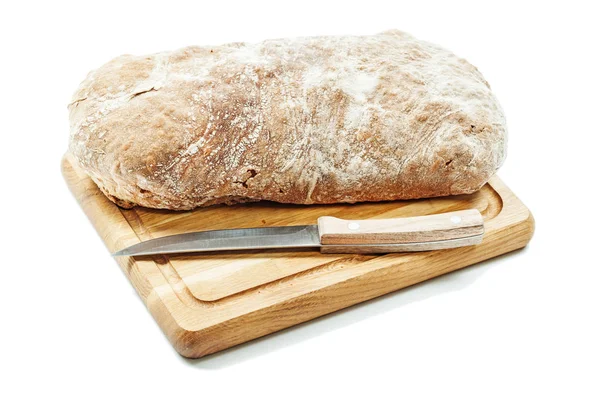 Loaf of bread on carving board with kitchen knife isolated — Stock Photo, Image