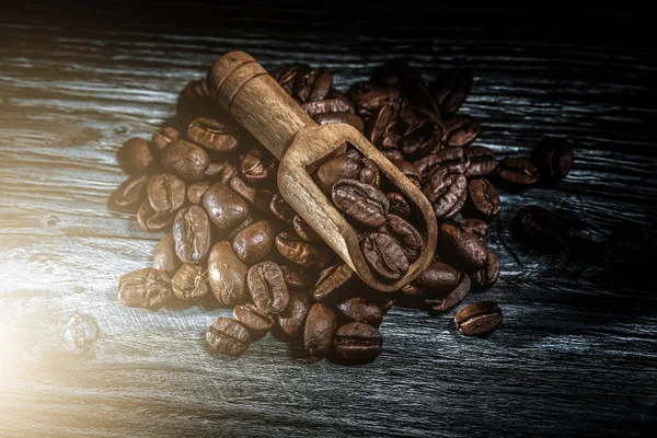 Pieczone nasiona kawy w szufelka na drewnianej płycie — Zdjęcie stockowe