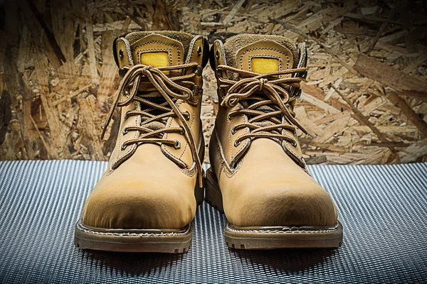 two brown working boots on plywood background