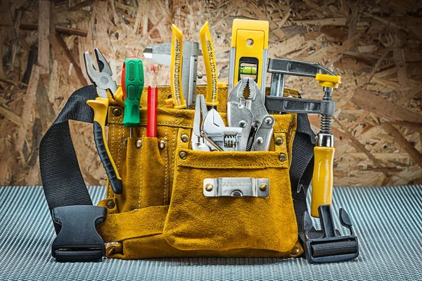 Cinto de ferramentas de couro com muitas ferramentas de construção em backgro de madeira compensada — Fotografia de Stock