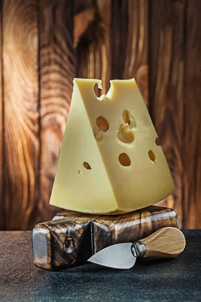 Vista verticale grande pezzo di latte maasdam formaggio su piccolo taglio — Foto Stock