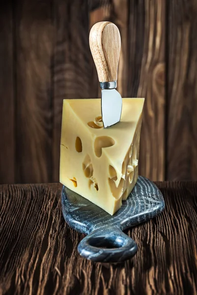 Vista verticale pezzo di latte maasdam formaggio con coltello su poco — Foto Stock